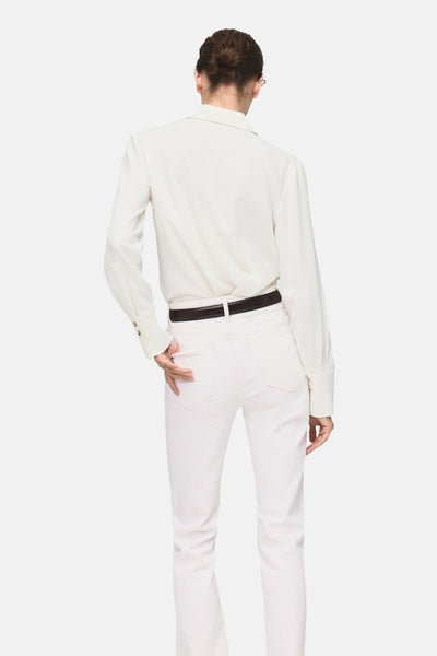 Ecru overhemd met lange mouwen van MANGO, met een bruine riem en een witte broek.