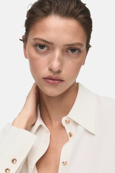 Ecru blouse met lange mouwen van MANGO, met decoratieve gouden knopen op de manchetten en een knoopsluiting.