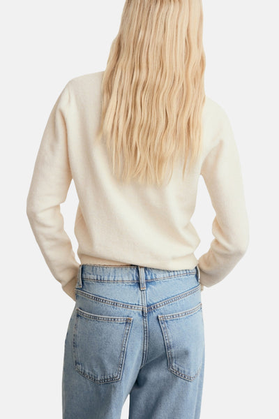 Cardigan écru de MANGO, porté avec un jean bleu clair, vue de dos.