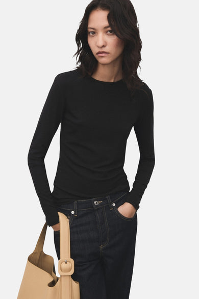 T-shirt noir à manches longues de MANGO, porté avec un jean foncé et un sac à main beige.
