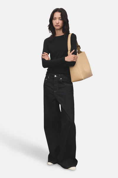 T-shirt à manches longues noir de MANGO, porté avec un jean large bleu foncé et un sac à main beige.
