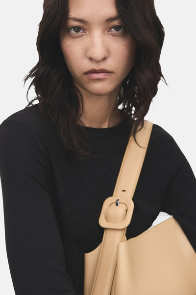 T-shirt noir à manches longues de MANGO, porté avec un sac à bandoulière beige.