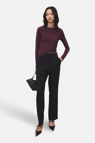T-shirt à manches longues bordeaux de MANGO, porté avec un pantalon à rayures et des chaussures à brides.