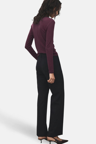 T-shirt bordeaux à manches longues de MANGO, porté avec un pantalon noir à rayures et des escarpins.