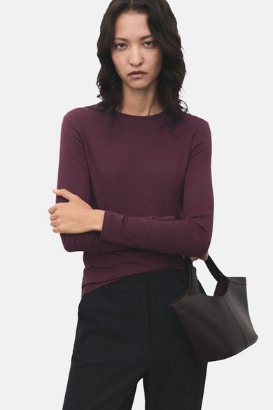 T-shirt bordeaux à manches longues de MANGO, porté avec un pantalon rayé et un sac à main.