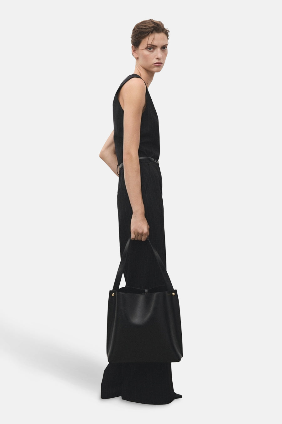 Blauwe jumpsuit van MANGO, gedragen met een dunne riem en een zwarte handtas.