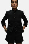 Blazer noir de MANGO avec fermeture boutonnée, poches à rabat et bijoux dorés.