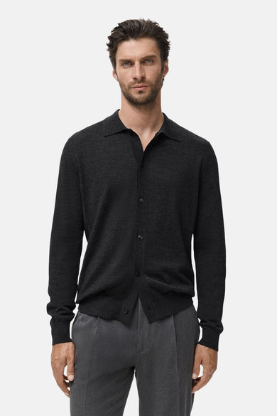 Grijze MANGO bodywarmer, met knopen aan de voorkant, gedragen met een bijpassende grijze broek.