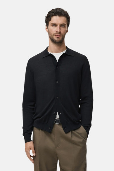 Blauwe MANGO-gilet, gedragen over een wit T-shirt met een klassieke bruine broek en een zwarte riem.