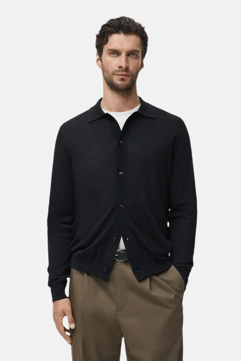 Blauwe MANGO-gilet, gedragen over een wit T-shirt met een klassieke bruine broek en een zwarte riem.