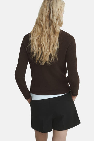 Pull à col rond brun de MANGO, porté avec un short noir et un t-shirt blanc, vue de dos.
