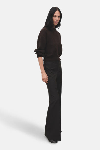 Pantalon brun de MANGO, coupe évasée, porté avec un pull en tricot marron uni.