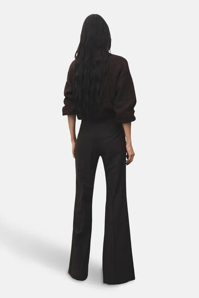Pantalon évasé brun de MANGO, porté avec un pull de couleur marron, vue de dos.
