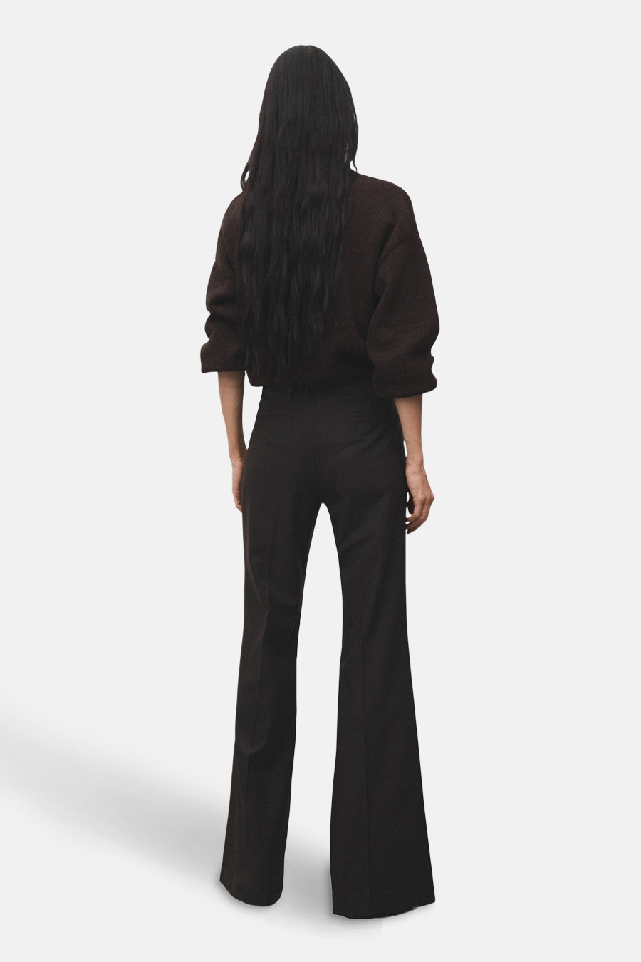 Pantalon évasé brun de MANGO, porté avec un pull de couleur marron, vue de dos.
