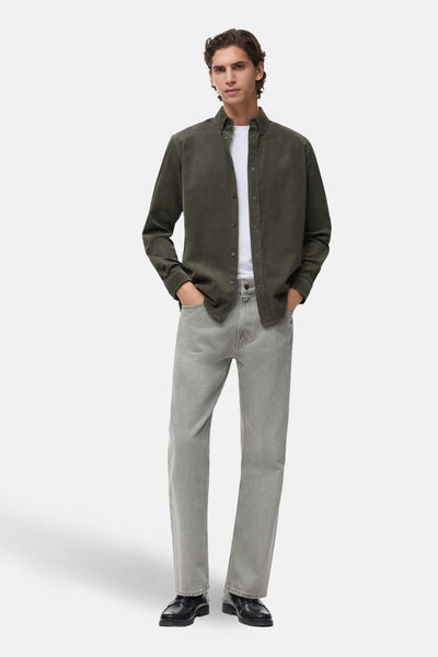 Chemise à manches longues verte de MANGO, portée ouverte sur un t-shirt blanc et un jean gris.
