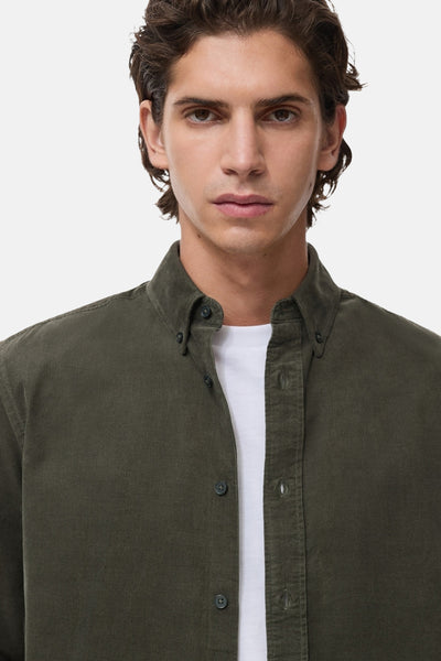 Chemise à manches longues verte en velours côtelé de MANGO, portée sur un t-shirt blanc, vue de face.
