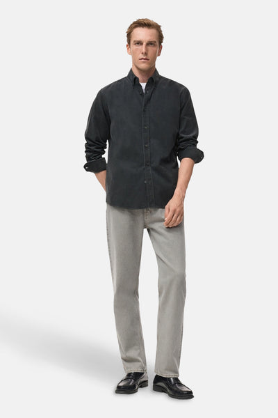Chemise à manches longues grise de MANGO, portée avec un t-shirt blanc, un jean et des chaussures noires.