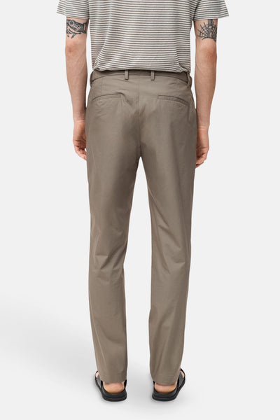 Pantalon brun de MANGO, coupe droite, porté avec un t-shirt à rayures et des sandales noires, vue de dos.
