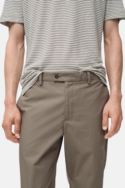 Pantalon marron de MANGO, coupe droite, porté avec un t-shirt rayé.