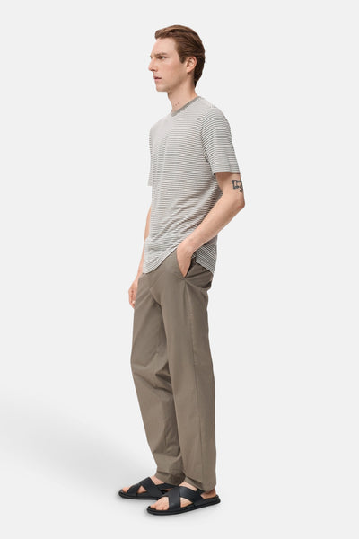 Pantalon de saison brun de MANGO, porté avec un t-shirt rayé et des sandales croisées.