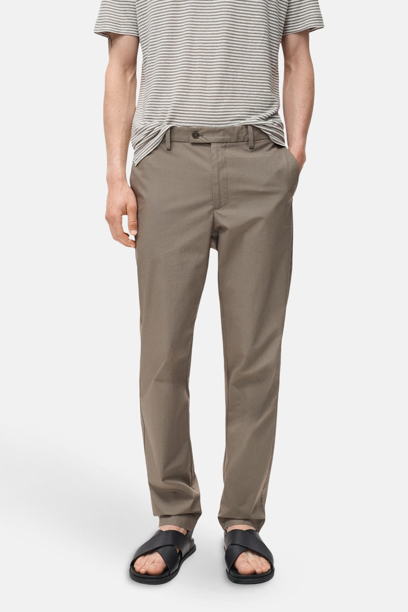 Pantalon marron de MANGO, porté avec un t-shirt rayé et des sandales croisées noires.

