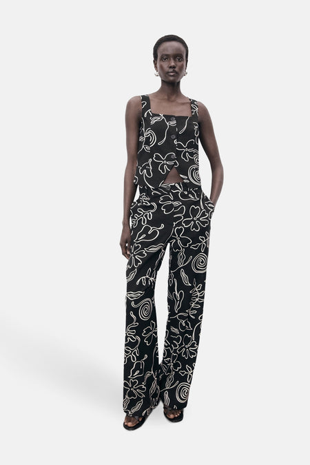 Zwart mouwloos bloesje van MANGO, met wit bloemenpatroon, gedragen met een bijpassende broek.