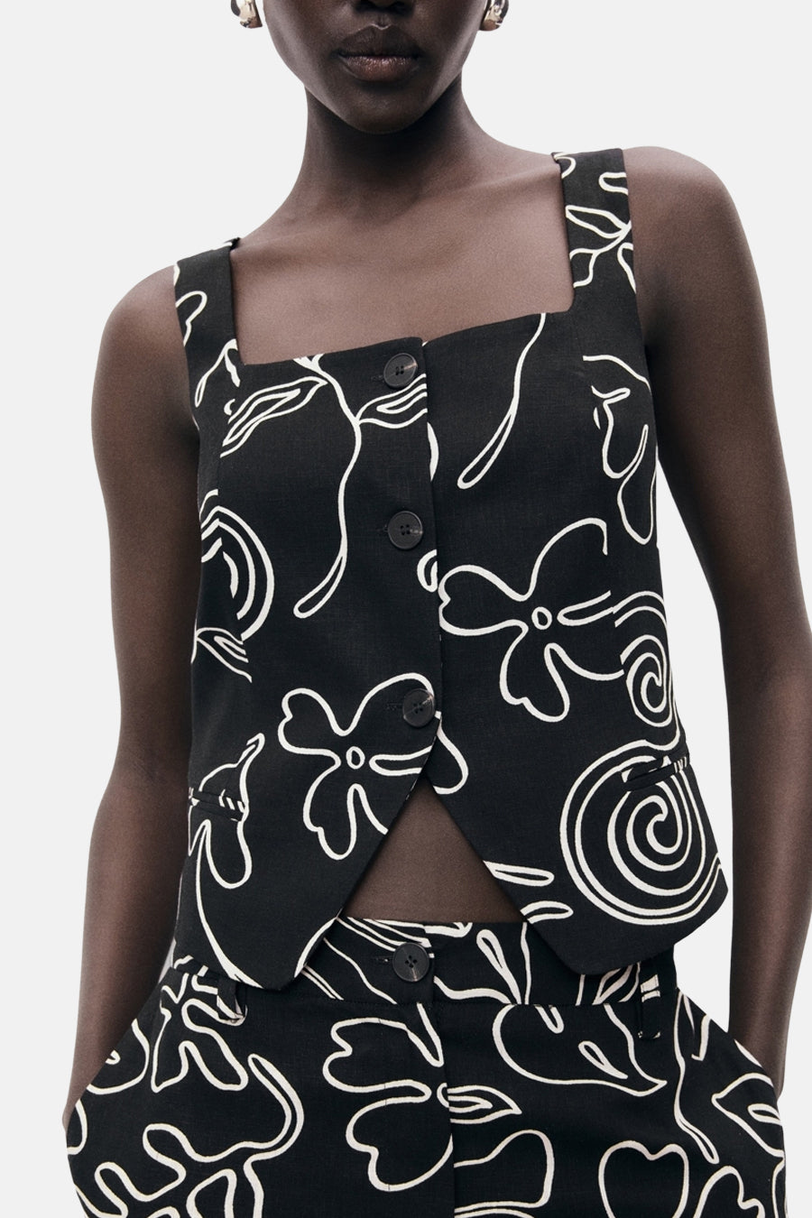Zwarte mouwloze blouse van MANGO, met witte bloemenprint en korte pasvorm.
