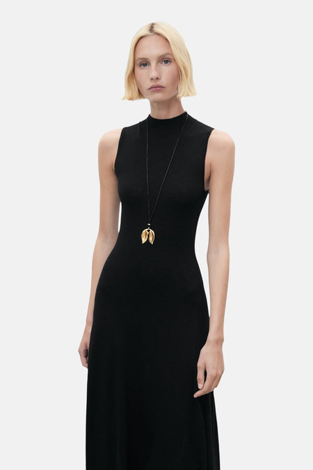 Zwarte nauwsluitende jurk van MANGO, met een gouden hangerketting.