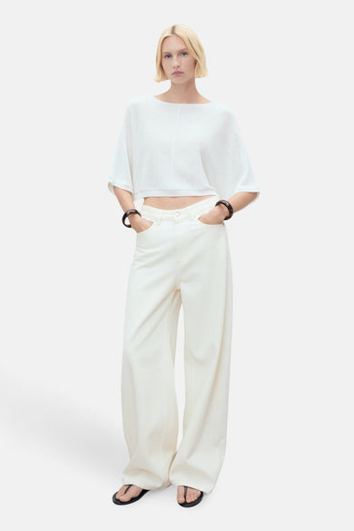 Witte rondehals trui van MANGO, gedragen met een witte broek met hoge taille en donkere armbanden.
