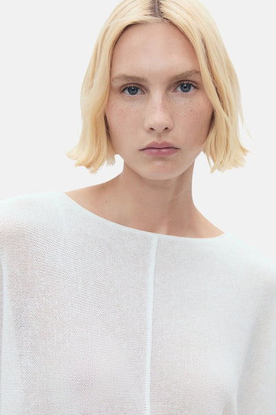 Pull à col rond blanc de MANGO, en maille fine, porté par une femme blonde aux yeux bleus.
