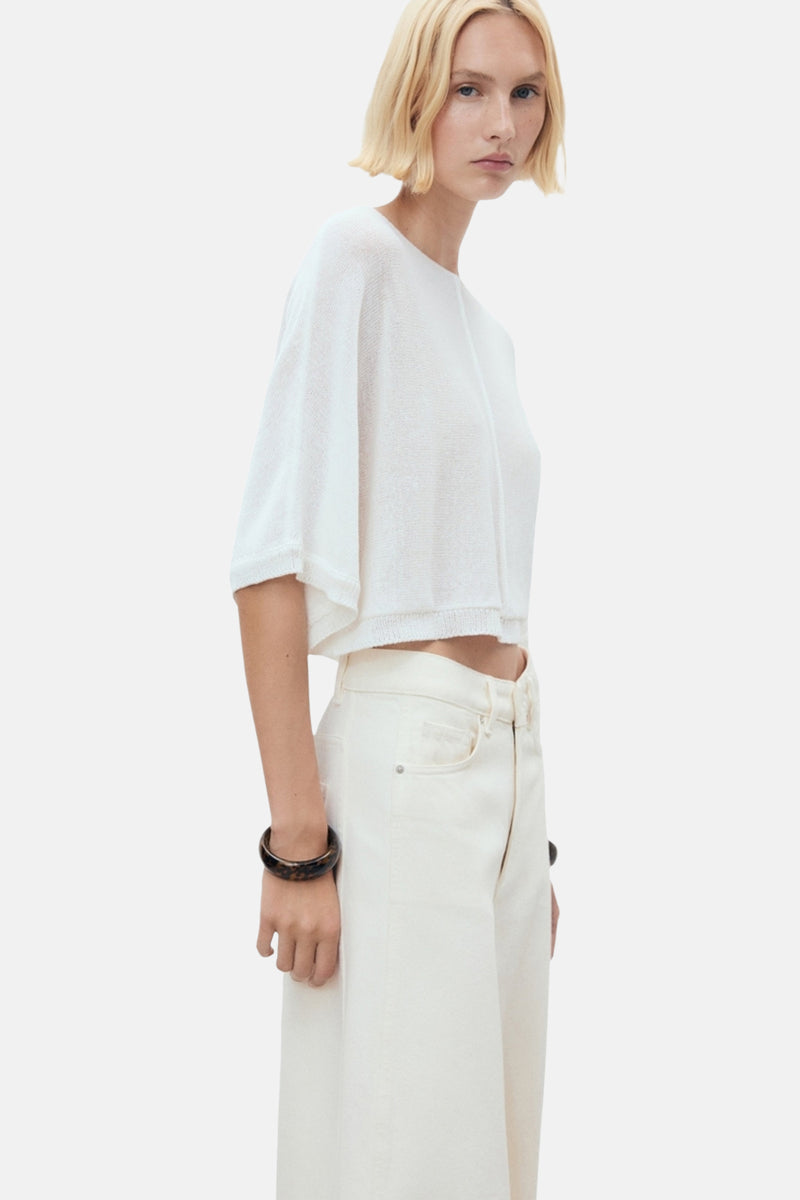 Witte rondehals trui van MANGO, korte pasvorm, gedragen met een high-waisted jeans en een donkere armband.