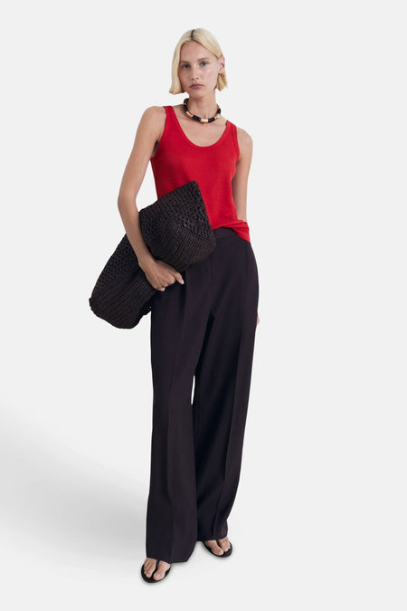 Rood hemdje van MANGO, gedragen met een wijde zwarte broek en een gevlochten handtas.