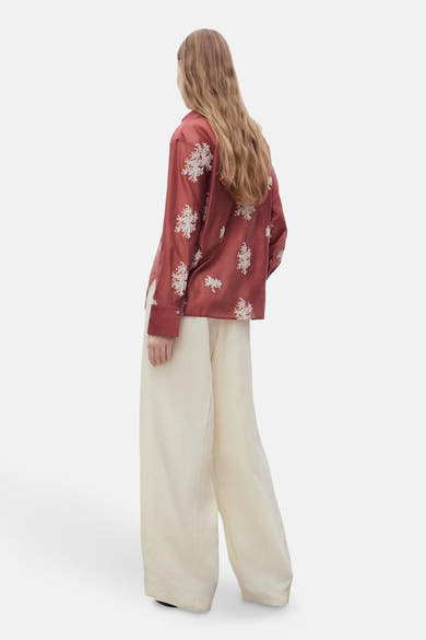 Bruin overhemd met lange mouwen van MANGO met geborduurde bloemenpatronen, gedragen met een wijde beige broek.