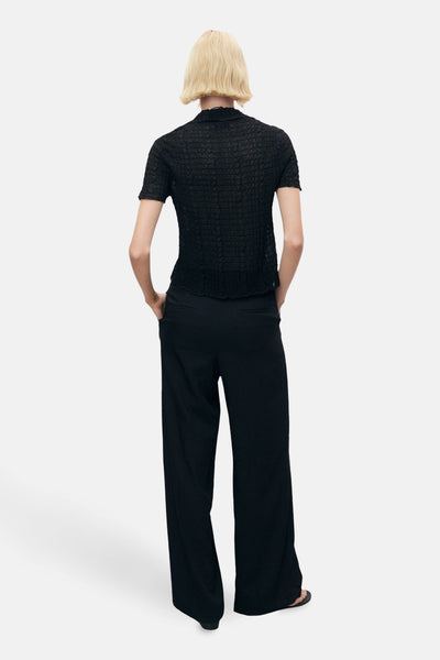 Zwarte broek van MANGO, wijde pasvorm, gedragen met een getextureerd topje en sandalen.