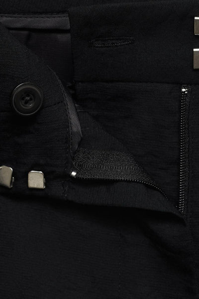 Pantalon noir par MANGO, détail de la fermeture éclair et du bouton.