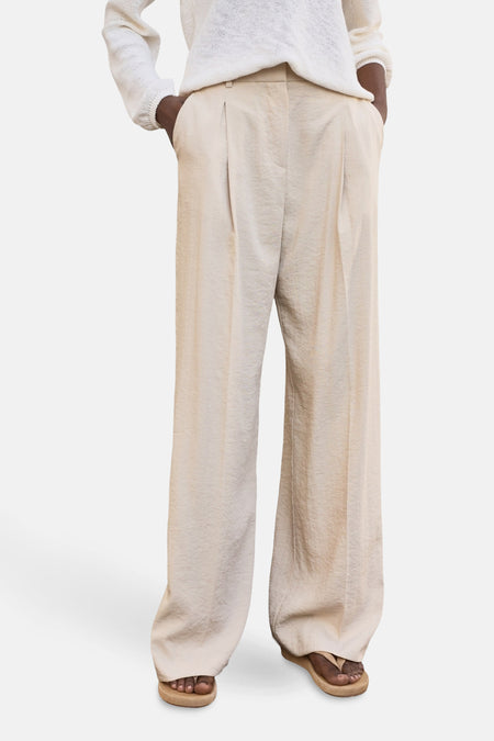 Beige wijde broek van MANGO, met plooien en zakken, gedragen met een witte trui en sandalen.