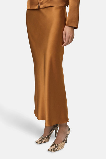 Lange bruine satijnen rok van MANGO, gedragen met slangenprint pumps.