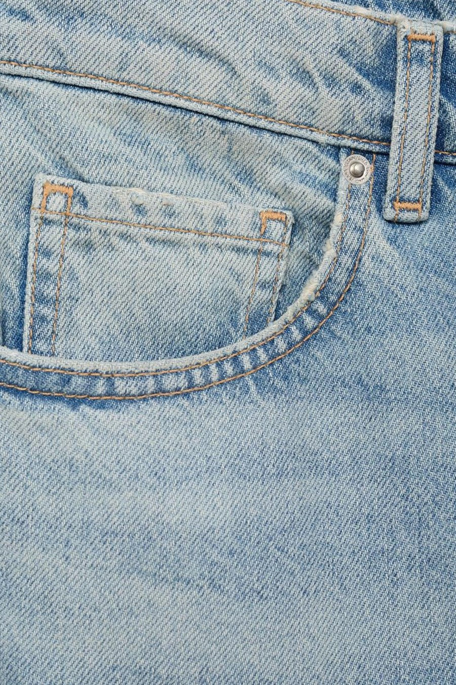 Jean évasé en denim bleu clair de MANGO, détail de poche gousset et passants de ceinture.
