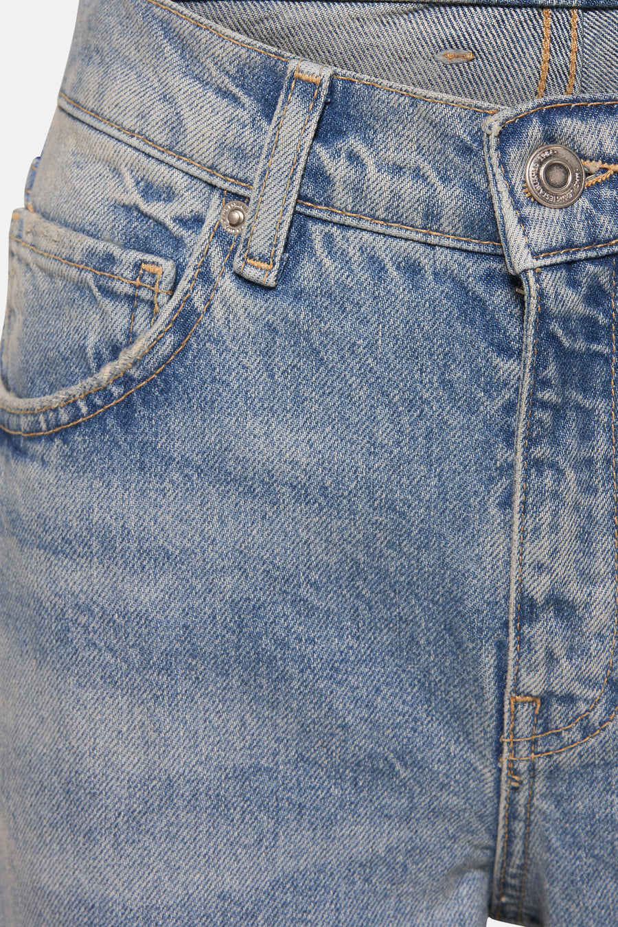 Jean évasé bleu clair de MANGO, détail de la poche et du bouton, tissu en denim délavé.