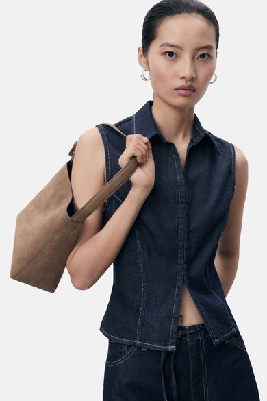 Chemisier sans manches en denim bleu foncé de MANGO, porté avec un sac à main en daim marron.
