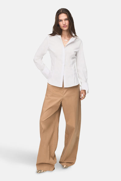 Wit overhemd met lange mouwen van MANGO, gedragen met een wijde broek en schoenen met slangenprint.