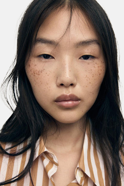 Multikleurig overhemd met lange mouwen van MANGO, met bruine en crèmekleurige verticale strepen, gedragen door een model.