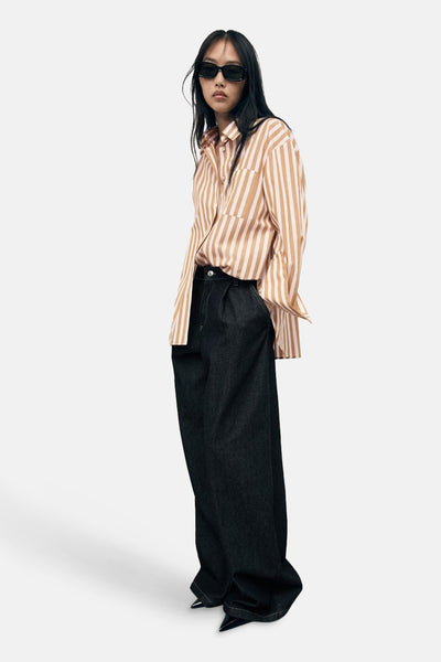 Chemise à manches longues multicolore de MANGO, à rayures, portée avec un pantalon ample noir et des lunettes de soleil.
