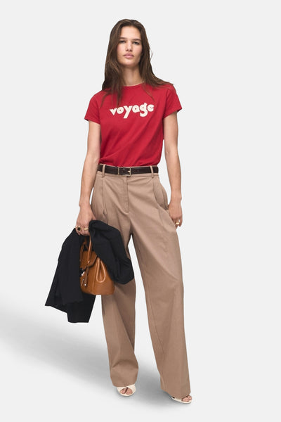 Rood T-shirt met korte mouwen van MANGO, met het woord "voyage" in het wit, gedragen met een beige broek en accessoires.
