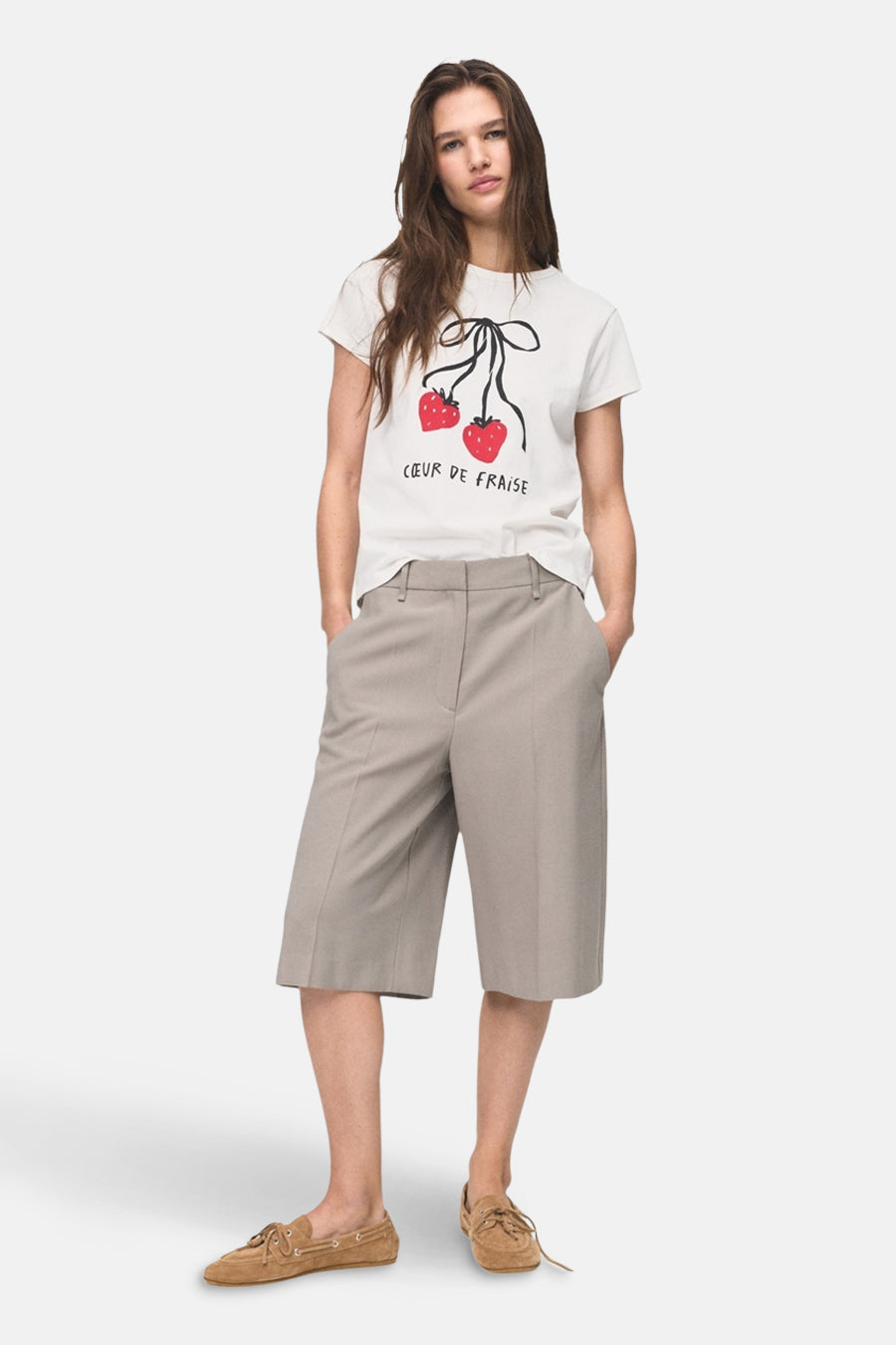 T-shirt blanc à manches courtes de MANGO, orné d'un motif de fraises et porté avec un bermuda et des mocassins marron.