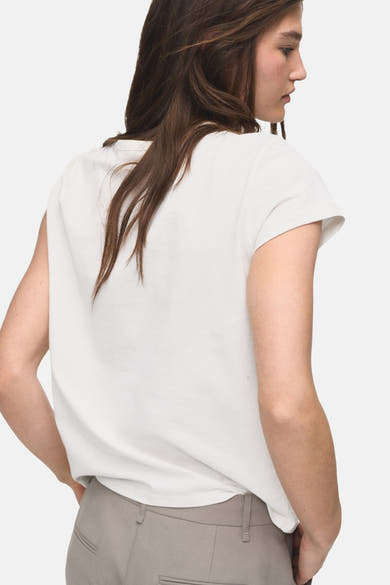 T-shirt blanc à manches courtes de MANGO, porté avec un pantalon beige, vue de dos.
