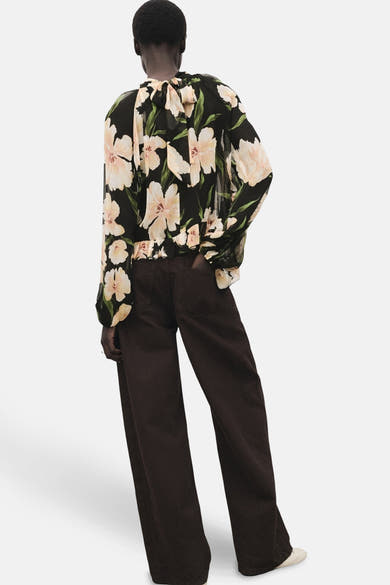 Chemisier à manches longues multicolore de MANGO, à motif floral et fermeture à nouer dans le dos, porté avec un pantalon marron.
