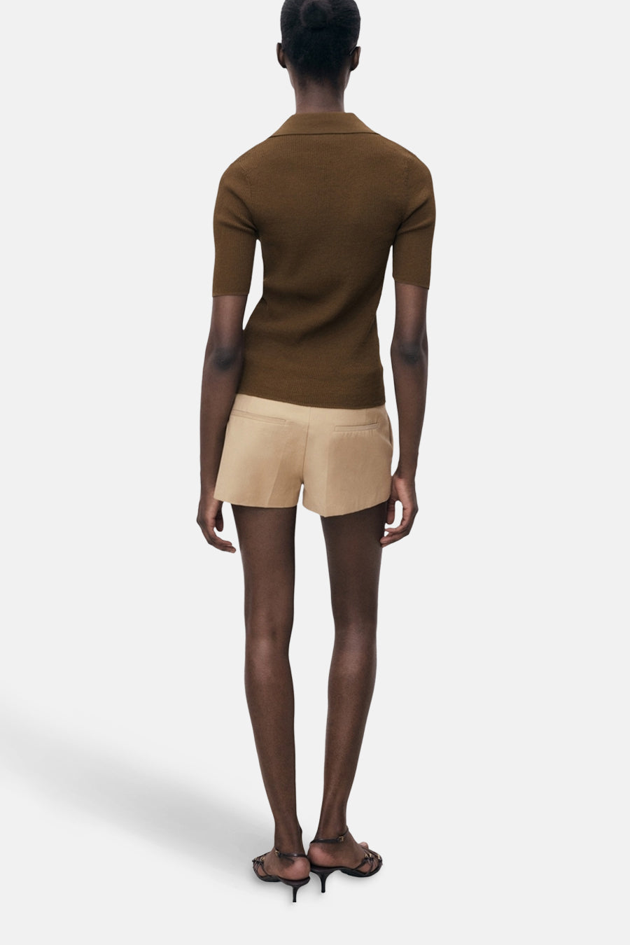 Korte mouwen poloshirt van MANGO, gedragen met een beige short en sandalen met hak, van achteren gezien.