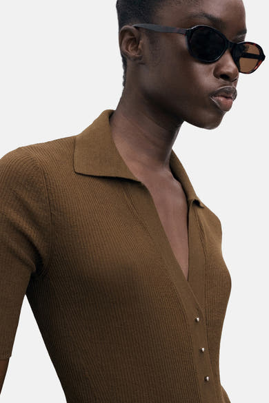 Geribde poloshirt met korte mouwen van MANGO, gedragen met een ovale zonnebril.