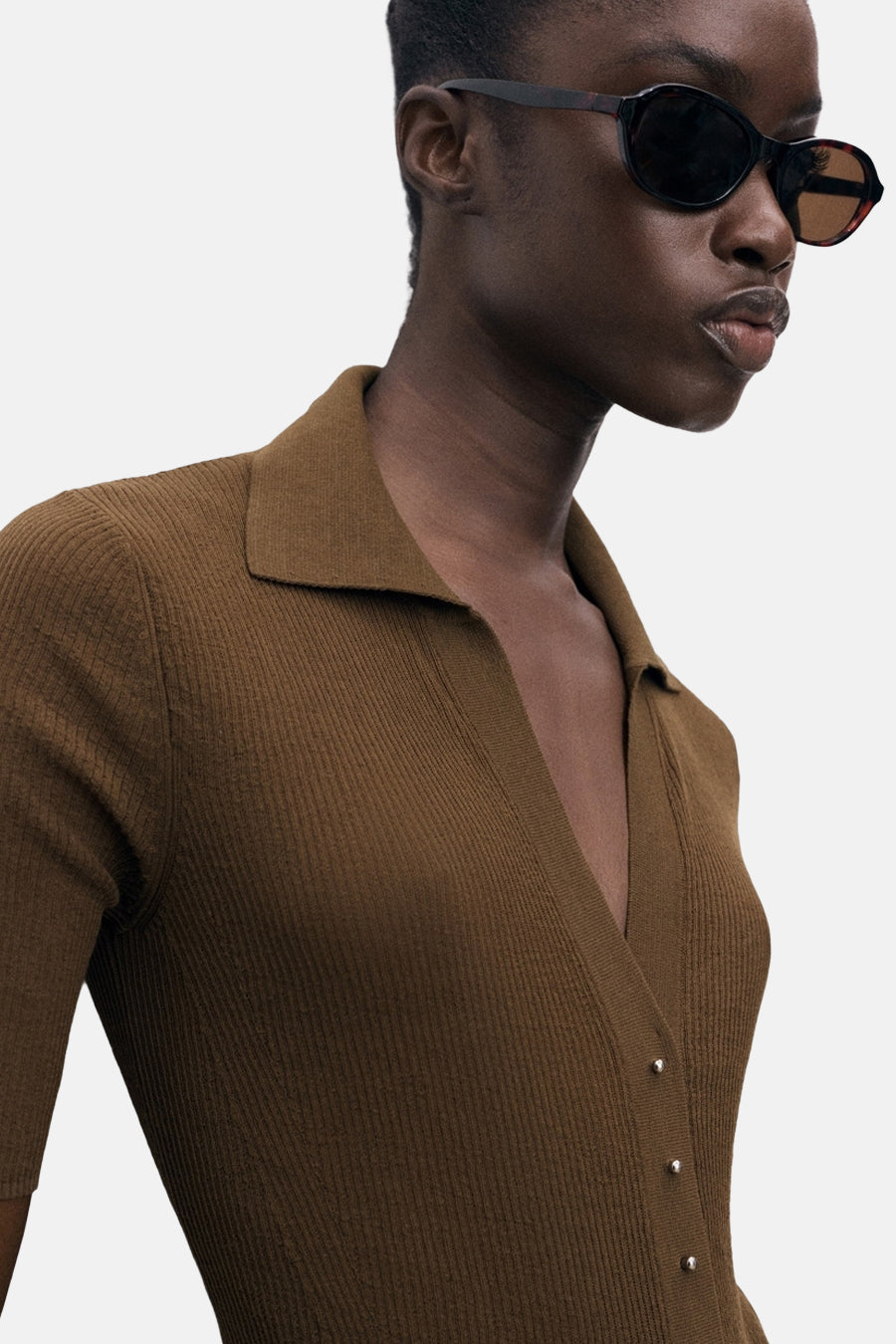 Geribde poloshirt met korte mouwen van MANGO, gedragen met een ovale zonnebril.